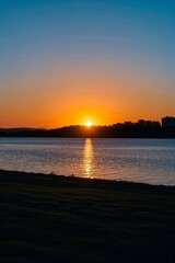 sunset over a body of water with a city in the distance