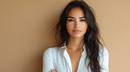 Fototapeta premium Hispanic woman crosses arms wearing white shirt, exudes confidence, showing professionalism, beauty, and inner calm.