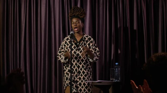 Joyful female African American stand-up artist coming on stage and tanking audience for applause