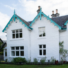 Scotish home with ornate, turquoise roof trim and white exterior.