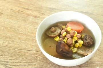 boiled corn with peanut and slice vegetable topping mushroom in Chinese herb soup on bowl