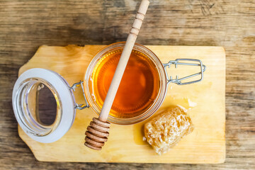 honey in a jar with honeycomb on a wooden table