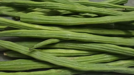 A close-up of freshly harvested green drumsticks, rich in nutrients and widely used in Indian cuisine for curries and stews.