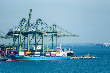 Gantry cranes over a cargo container ship in the port of Singapore. Cargo operations in process. 