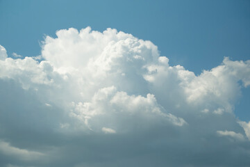 Fluffy white cumulus clouds drift across a clear, bright blue sky on a sunny day