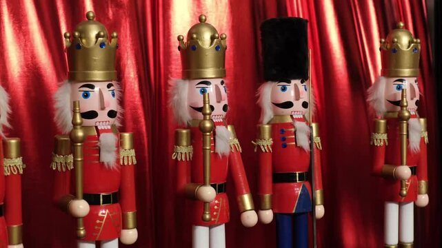Nutcracker soldiers stand in uniform formation against a red curtain. Dressed in traditional attire with gold crowns, each holds a staff. Perfect for holiday and Christmas themes.