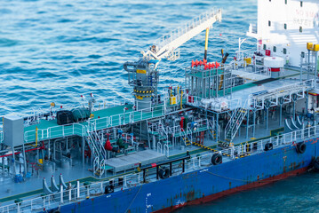 Close-up aerial view on the tanker ship, fuel bunker barge in the container terminal, she is...