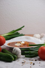 A plate of borscht with chasnok and on a wooden table.
