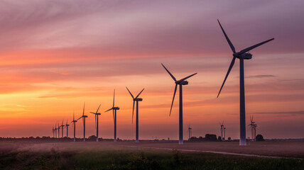 A breathtaking sunset frames the blades of wind turbines spinning in the wind