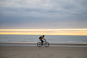 Obraz premium man riding bicycle on North sea coast in Denmark