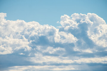 A cluster of cumulus thunderclouds in a bright blue sky during the daytime. CLOUD DANCER 11- 42011, color of the year 2026, pantone
