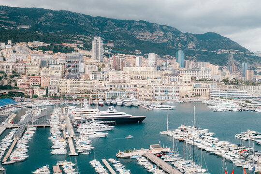 Luxury yachts docked in marina with city skyline and mountains in the background, Port Hercule, Monaco
