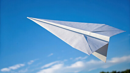 Paper airplane soars through clear blue sky, evoking sense of freedom and adventure