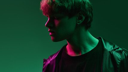 Side profile of young man with peaceful expression under vibrant magenta and green lights in...