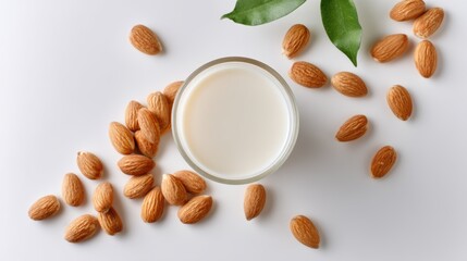 Almond Milk in Glass Bowl Surrounded by Almonds and Green Leaves on White Background