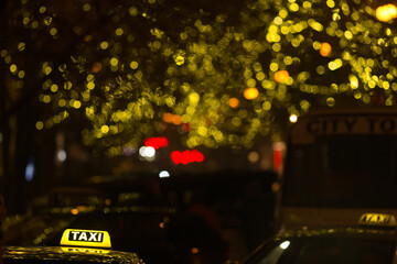 The urban street comes alive at nighttime, filled with taxis and adorned with festive lights that...