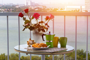 Breakfast with coffee, fresh croissants and orange fruit on hotel balcony