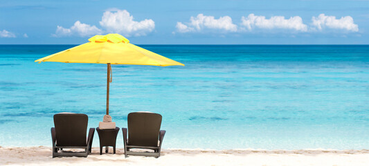  Beach scene with two beach chairs and yellow sun umbrella. Summer vacation on tropical sea. Travel destination