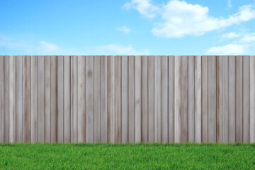 wooden fence with green grass and blue sky in the background