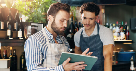 Men, barista and tablet with discussion at cafe with sales report, coach and review schedule at...