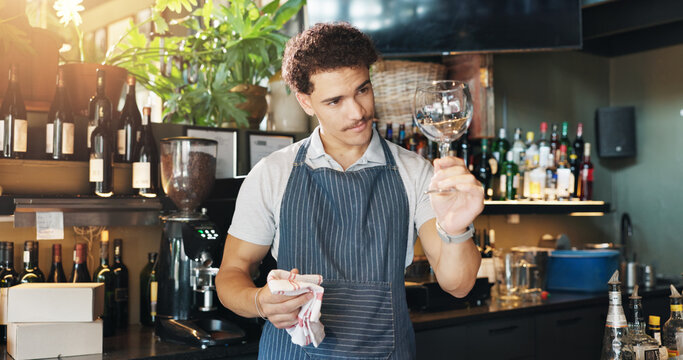 Waiter, man and cleaning glass with cloth for hygiene, dust and service for drinks at restaurant. Person, bartender and check for dirt with smile, shine and career with inspection at small business - Powered by Adobe