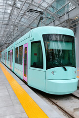 Modern turquoise tram waiting at station platform