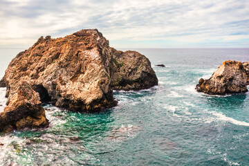 Stunning coastal landscape along California's Highway 1, featuring rugged rocky formations, and the vast blue ocean. A breathtaking natural scene showcasing the raw beauty of the Pacific coastline