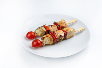 Grilled chicken kebab on skewers with tomatoes on a white plate