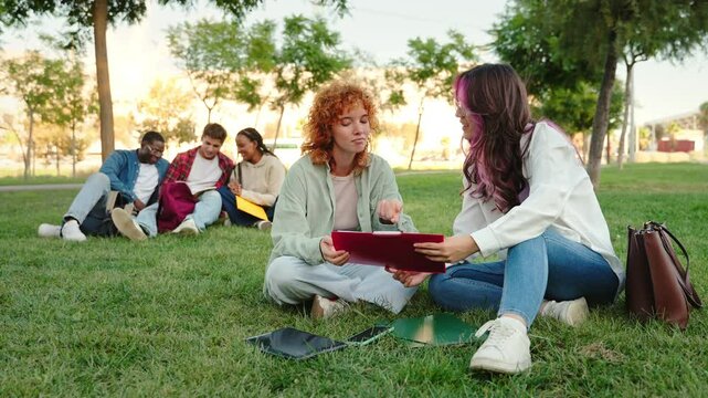 University student girls sitting on the grass working and learning together