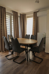 round light wood table surrounded by 6 brown chairs in a modern classic interior
