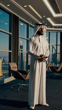 Handsome man with saudi arabia dish dasha working in his business office of Dubai. Portraits of a successful businessman in traditional emirates white dress.	