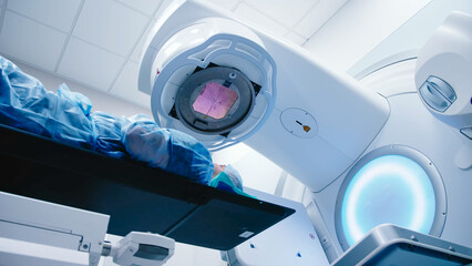 A young man undergoing radiation therapy for cancer in a state-of-the-art oncology clinic using a...
