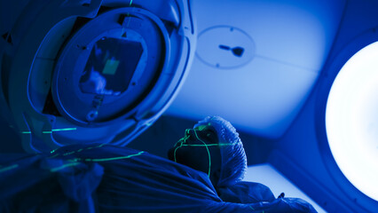 A young man undergoing radiation therapy for cancer in a state-of-the-art oncology clinic using a...