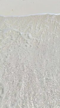 Top view of tropical beach with white sand and clear blue ocean turquoise water in natural sunlight, minimalist peaceful scenery background, relaxation, hotel, summer escape, Maldives island vacation