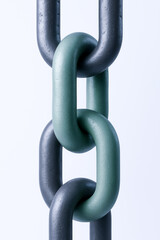Fototapeta premium close up of interlocking metal chains, featuring green link among black ones, symbolizes strength and connection