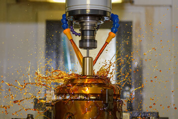 Close up scene the CNC milling machine finishing cut the brass shell mold parts with oil coolant...