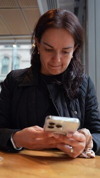 Mujer latina texteando en cafeter&iacute;a 