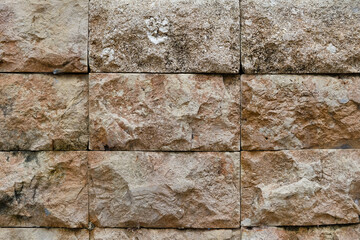 A rough stone surface with cracks and natural pores, giving an ancient and authentic impression, often used as a decorative element in buildings.