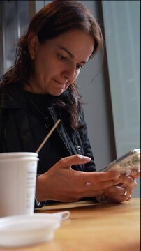 Mujer latina texteando en cafeter&iacute;a 