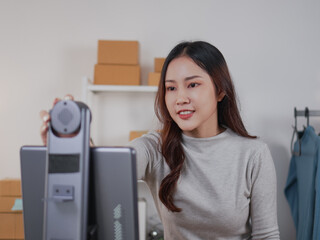 A smiling woman hosts a livestream infront of live broadcast machine, engaging with viewers while...