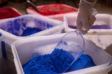 Hand in Glove Scooping Blue Pigment from Container  