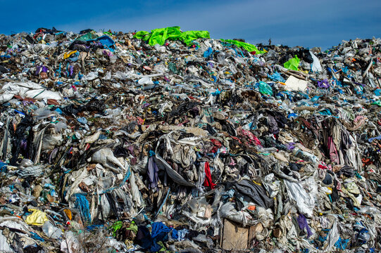 A vast expanse of textiles and clothing piled high at a landfill, reflecting the growing issue of waste and environmental impact