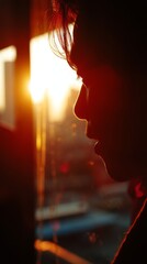 A person in profile silhouetted against the sunset, bathed in cherry red and butter yellow tones, creating a warm, contemplative, and visually poetic scene.