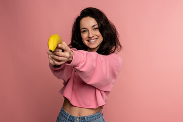 Cheerful cute brunette posing during the studio photo shoot on the pink background with her...