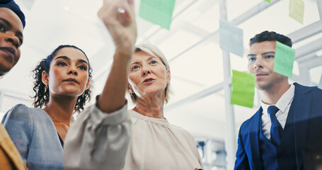 Glass wall, management and writing with business people in office for planning or strategy. Brainstorming, coaching and sticky notes with employee team in low angle for collaboration or discussion