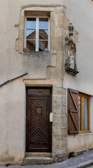 Fototapeta premium Old building facade featuring wooden door, iron balcony, and geometric stone wall pattern.For the background of your photos and collages.
