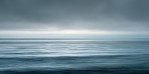 Fototapeta premium calm ocean water with hazy sky in soft blue and grey tones