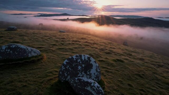 Misty sunrise over rolling hills and lush landscape with dramatic lighting