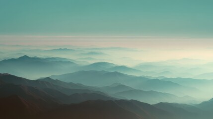 Obraz premium Layered mountain ridges fading into soft atmospheric haze at dawn