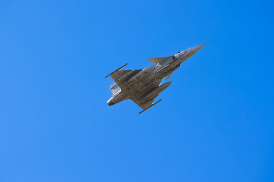 Stealth Saab JAS 39 Gripen fighter jet with afterburner under clear blue sky